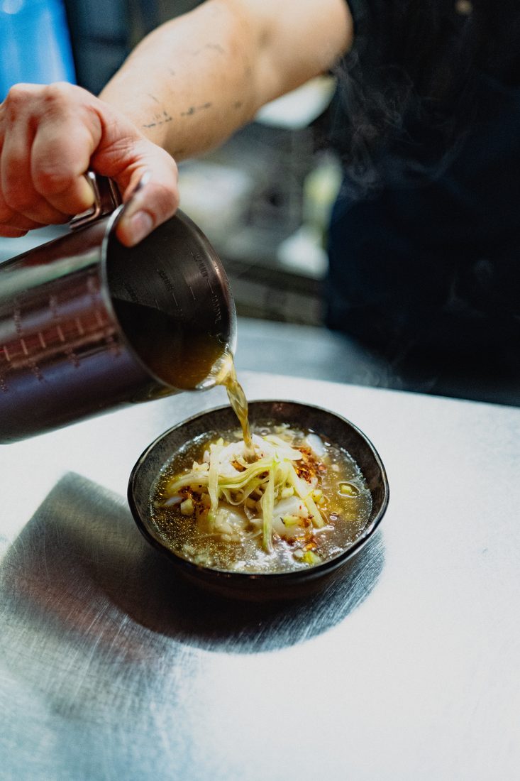 Dressage d'un plat, bouillon versé sur une assiette dans un restaurant à Toulouse